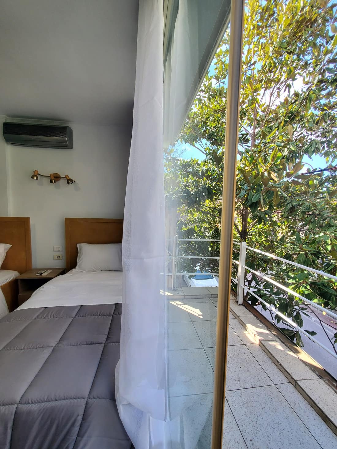 Room opening onto a balcony with trees outside