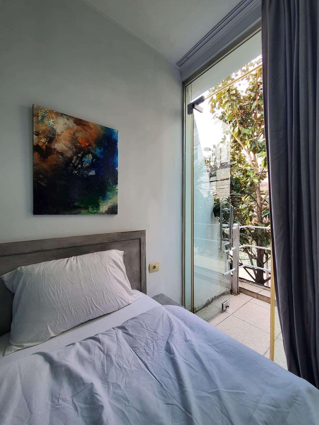 Bed beside a glass door with greenery outside