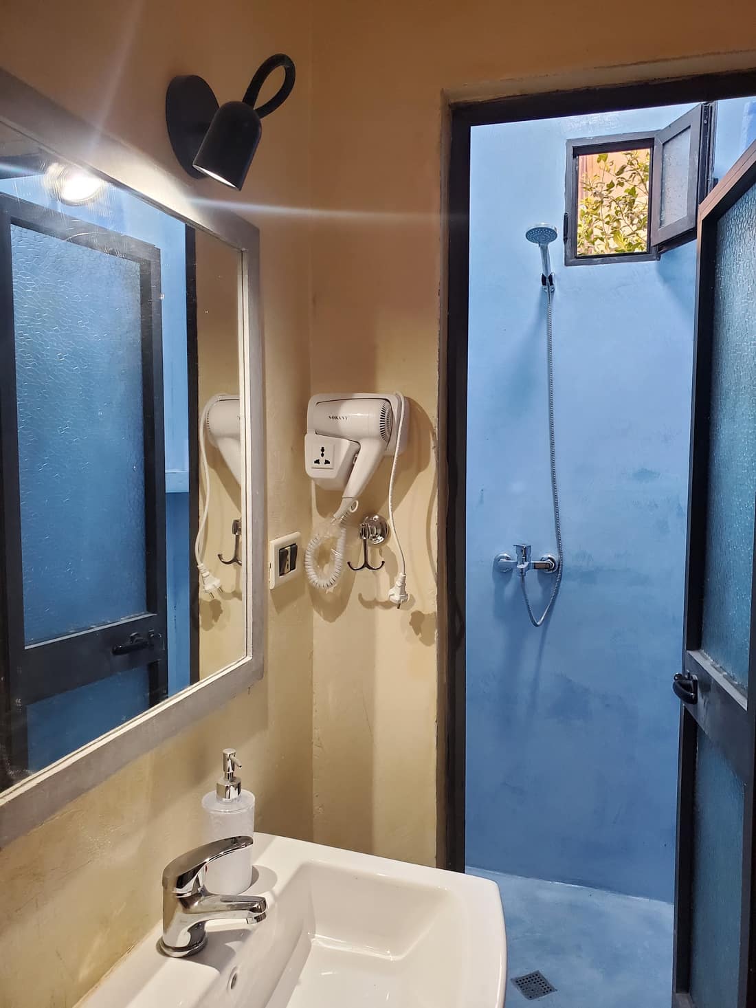 Vanity with sink and mirror beside a blue-tiled shower room