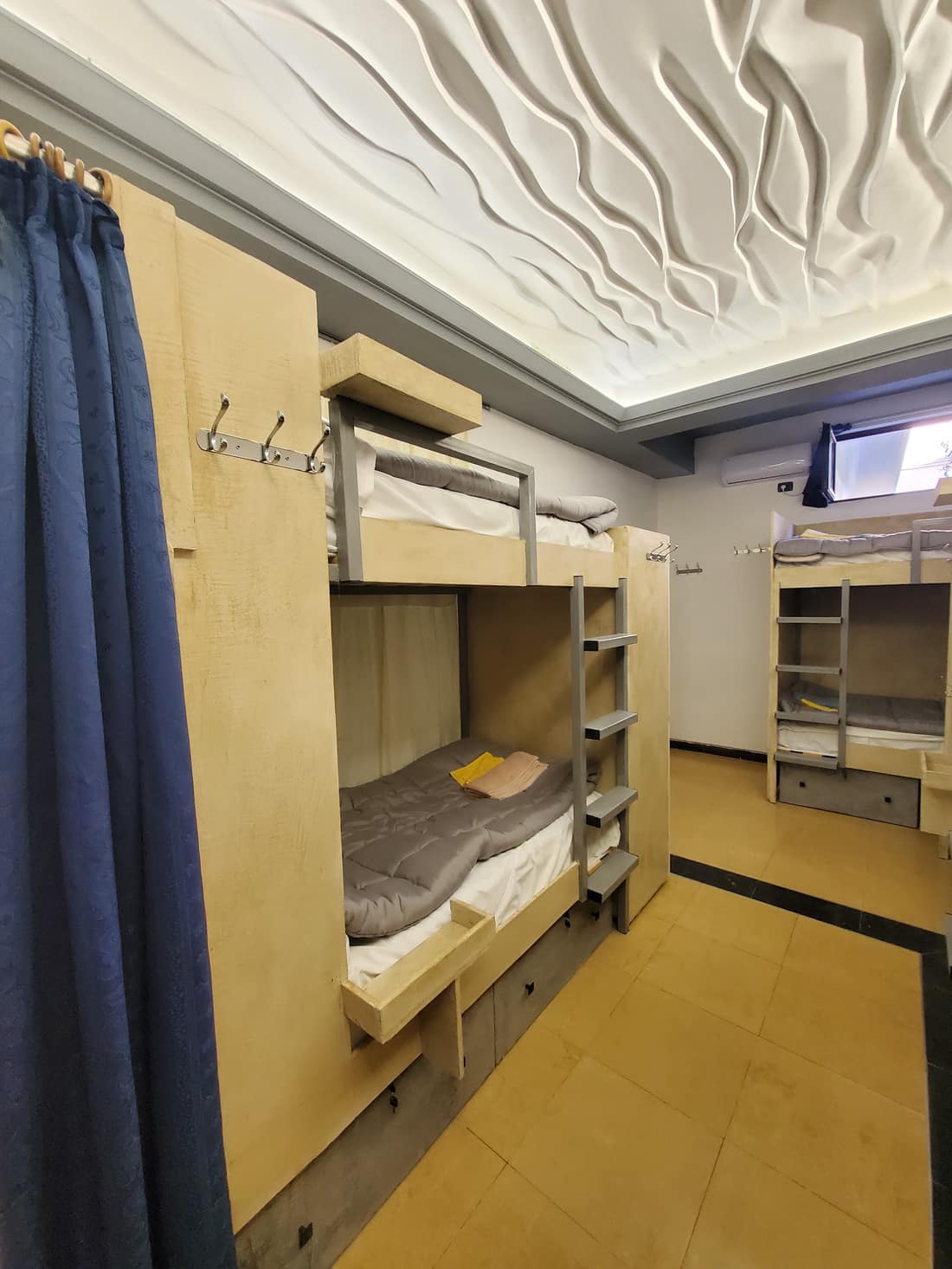 Bunks under the sculpted ceiling with a blue curtain