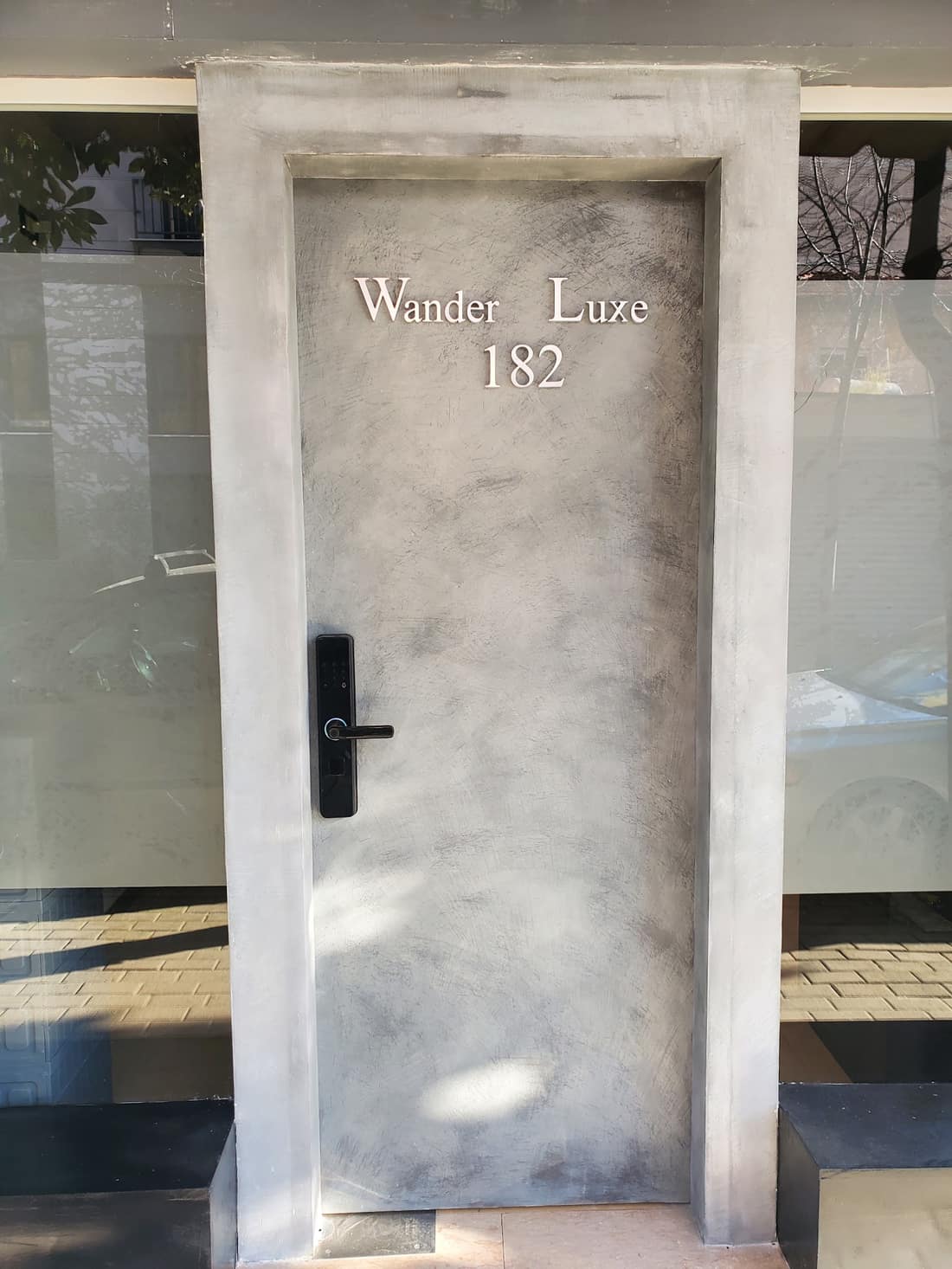 Textured grey front door with the Wander Luxe name and the number 182 set into it