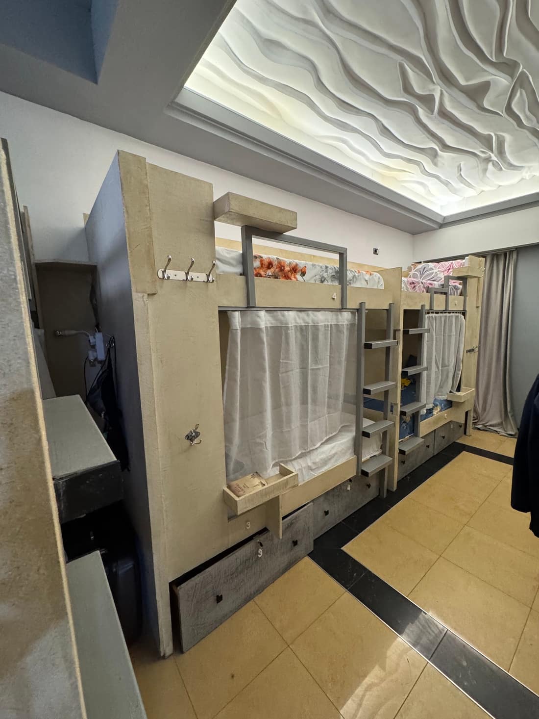 The dorm with curtained bunks and patterned ceiling