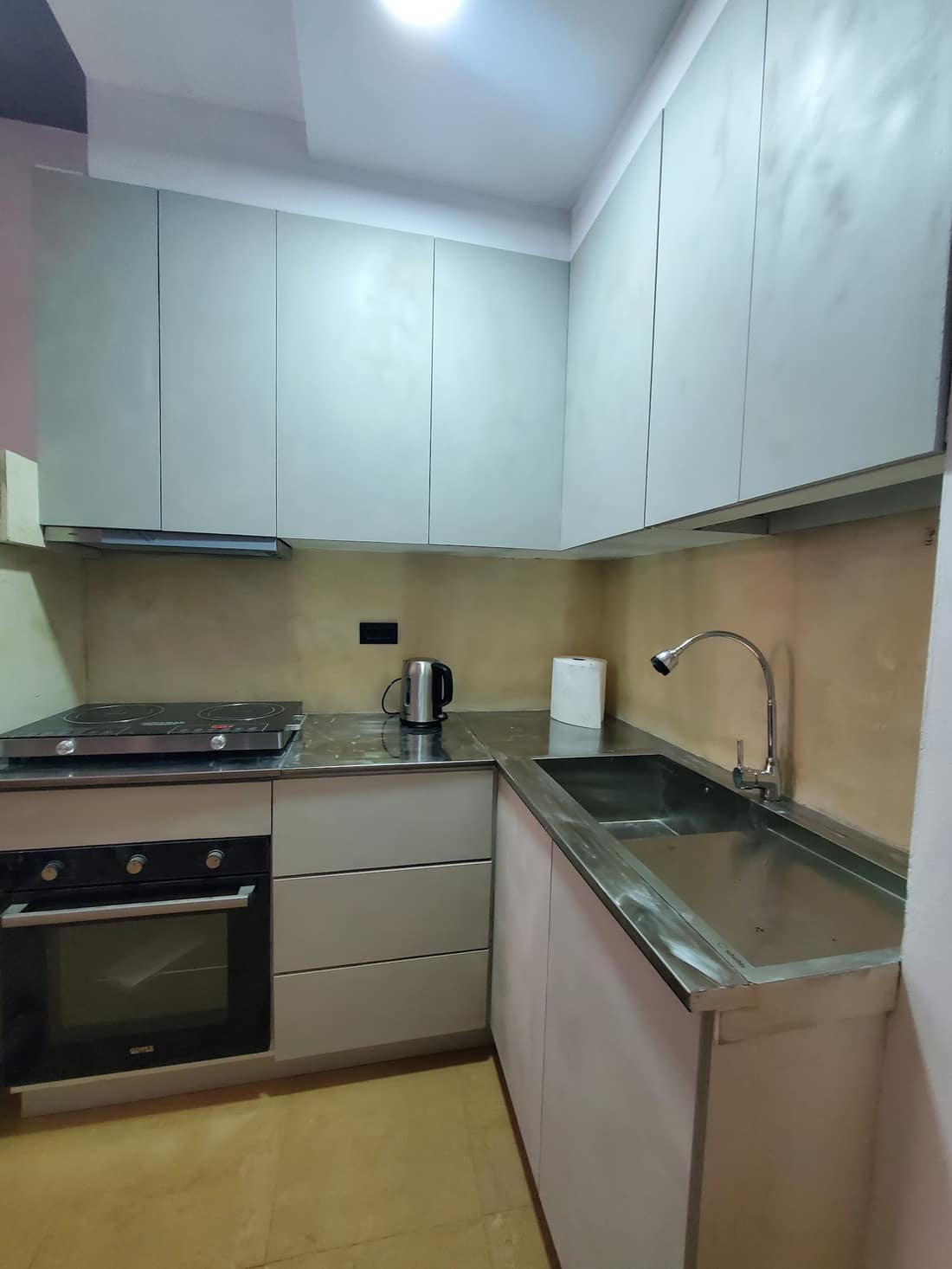 Fitted kitchen with oven, hob and pale cabinets