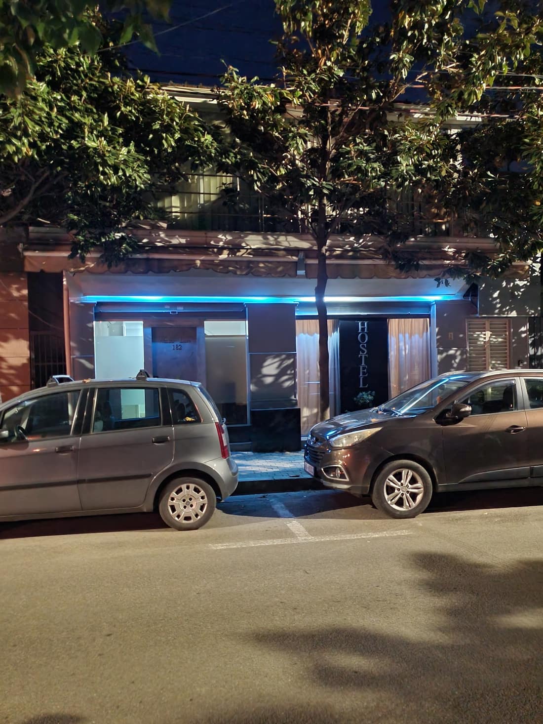 The hostel front at night with blue light along the facade