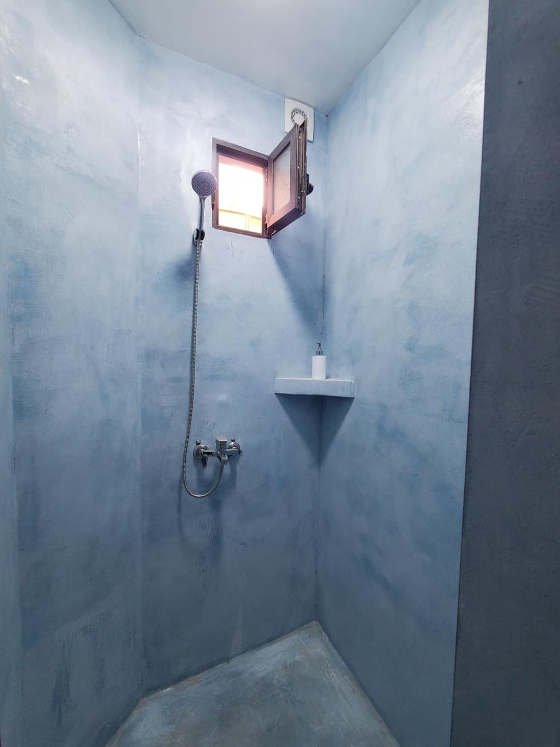 Blue-plastered shower room with a small window